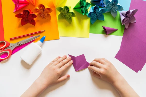 As mãos do origami de menina põem flores do papel da cor de tendência Violeta. Lição de origami. Flat lay estilo . — Fotografia de Stock