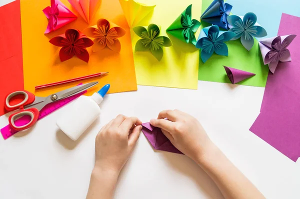 Kezében a lány origami helyezi virágok papír lila trend színe. Lecke origami. Lapos feküdt stílus. — Stock Fotó