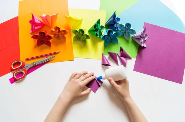 Hände des Mädchens Origami legt Blumen aus Papier der violetten Trendfarbe. Lektion des Origami. flache Verlegestile. — Stockfoto