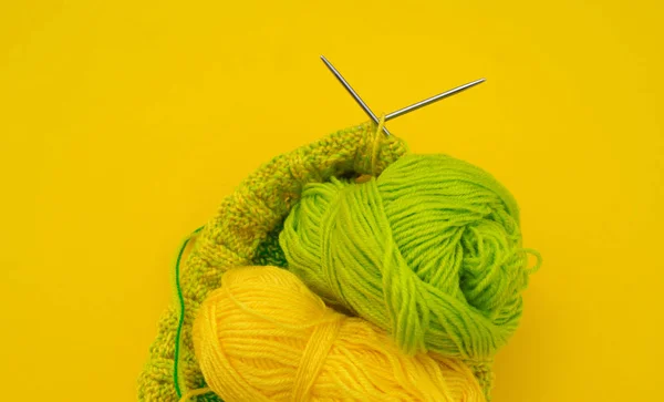 黄色和绿色的羊毛大衣躺在桌子上。最喜欢的爱好是编织. — 图库照片