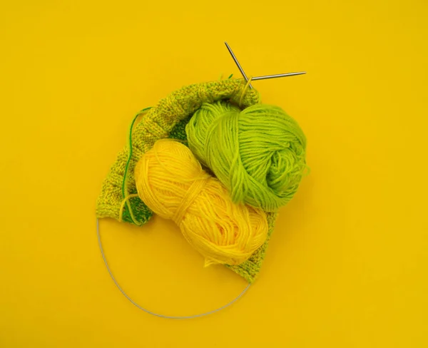 Des manteaux jaunes et verts de laine reposent sur la table. passe-temps préféré est le tricot . — Photo