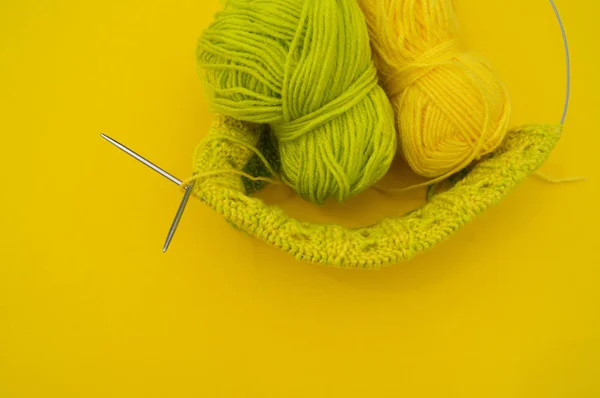Des manteaux jaunes et verts de laine reposent sur la table. passe-temps préféré est le tricot . — Photo
