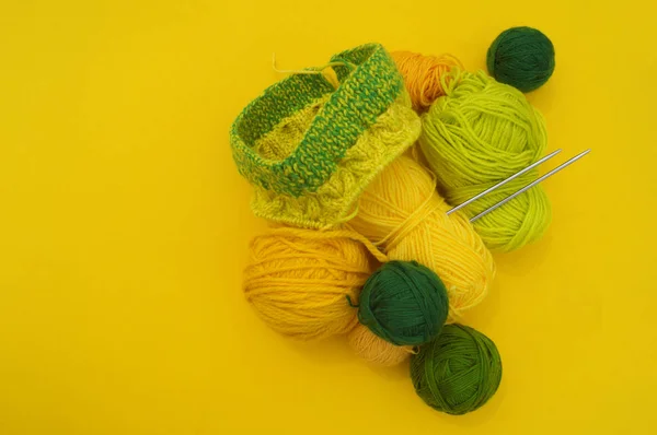 Na stole leží žluté a zelené pláště vlny. Nejoblíbenější hobby je pletení. — Stock fotografie