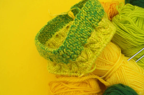 Casacos amarelos e verdes de lã estão sobre a mesa. hobby favorito é tricô . — Fotografia de Stock