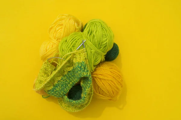 黄色和绿色的羊毛大衣躺在桌子上。最喜欢的爱好是编织. — 图库照片