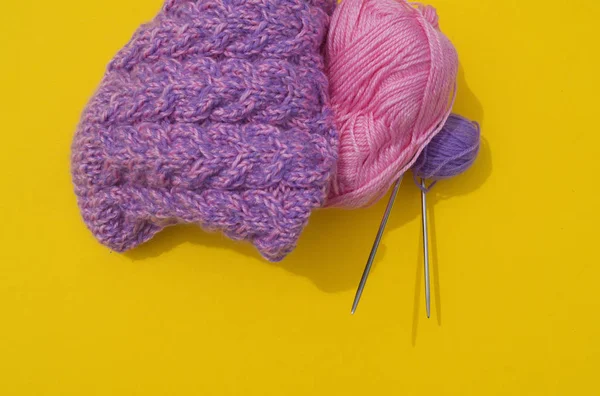 Des couches de laine rose et violette se trouvent à côté d'une casquette non connectée. Fond jaune . — Photo