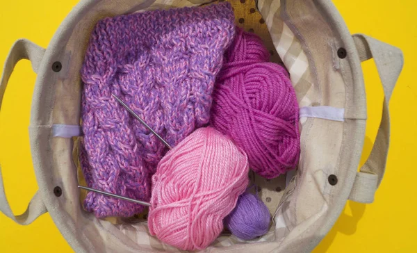 Os emaranhados de fios lilás, rosa e roxo estão em uma cesta em um fundo amarelo. hobby favorito é criativo . — Fotografia de Stock