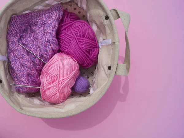 Lilac, pink and purple tangles of threads lie in a basket on a pink background. — Stock Photo, Image