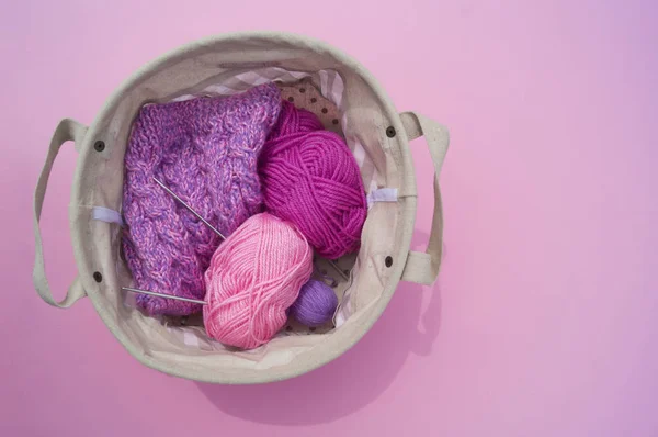 Lilac, pink and purple tangles of threads lie in a basket on a pink background. — Stock Photo, Image
