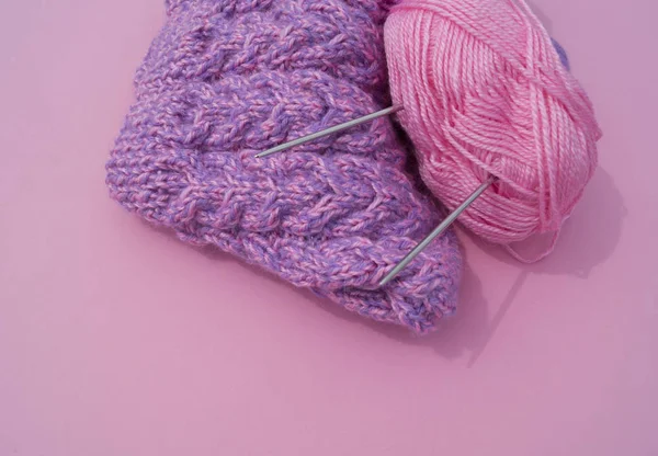 O processo de tricotar uma tampa lilás. Fios de lã em um fundo rosa. Fios acolhedores . — Fotografia de Stock