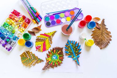 Çocuk sonbahar yaprağına resim çizer.