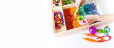 İçinde gökkuşağı pirinci olan duyusal kutu. Montessori materyali bebek Boşluğu Kopyala