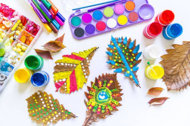 Çocuk sonbahar yaprağına resim çizer.