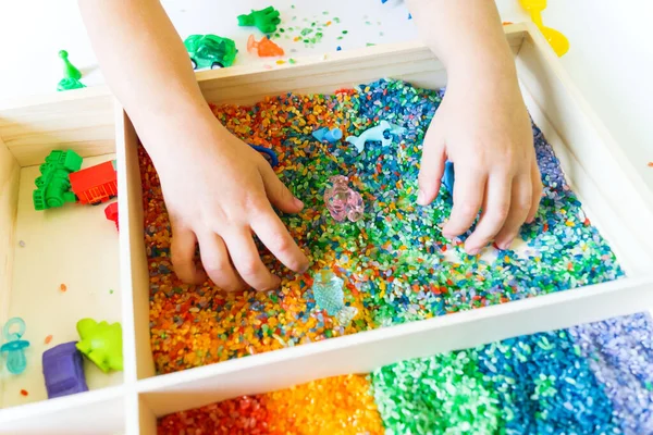 İçinde gökkuşağı pirinci olan duyusal kutu. Montessori materyali bebek