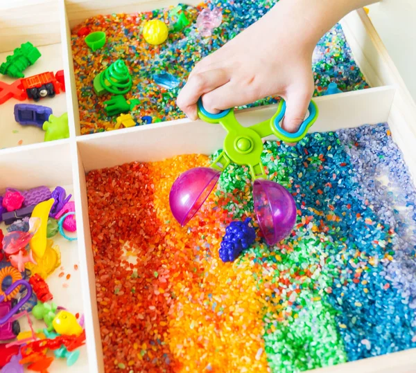 İçinde gökkuşağı pirinci olan duyusal kutu. Montessori materyali bebek