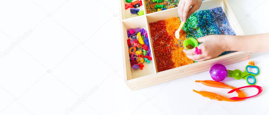 Sensory box with rainbow rice inside. Montessori material baby Copy Space