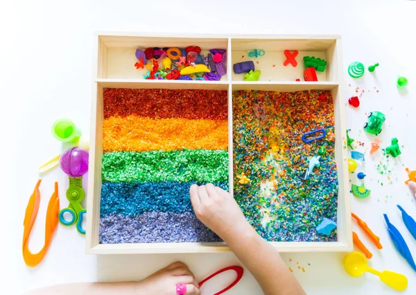 İçinde gökkuşağı pirinci olan duyusal kutu. Montessori materyali bebek