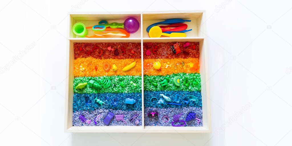 Sensory box with rainbow rice inside. Montessori material baby Copy Space