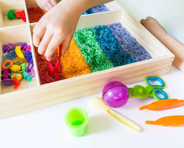 İçinde gökkuşağı pirinci olan duyusal kutu. Montessori materyali bebek