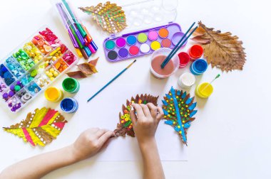 Çocuk sonbahar yaprağına resim çizer.