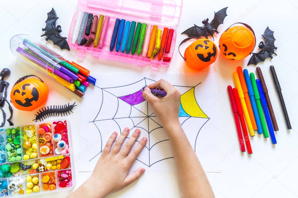 Child draws a rainbow cobweb. Drawing halloween Crayons