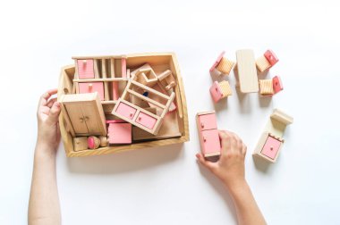 Montessori kumaşı. Oyuncak ev için ahşap mobilyalar. Beyaz arka plan. Bir çocuk için doğal bir oyuncak. Bir çocuğun elleri. Çevre dostu