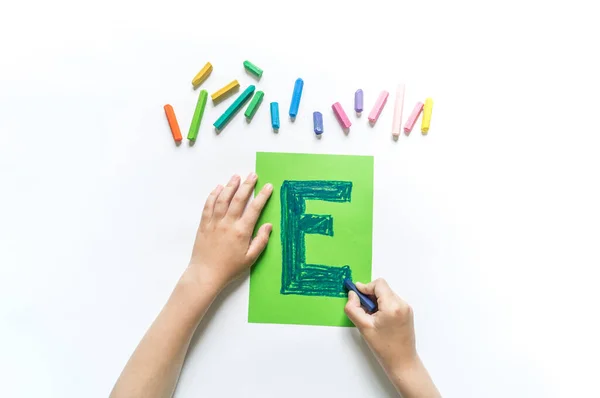 Children\'s hands write the letter E chalk. White background. Write ABC. Office Back to School