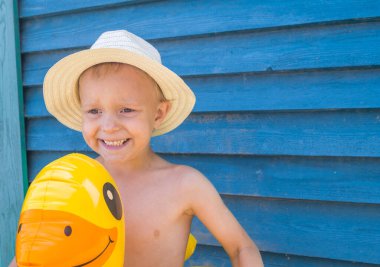 Hasır şapkalı lastik ördekli çocuk. Ahşap arka. Taze trend rengi. Havuz gezisi