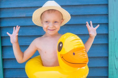 Hasır şapkalı lastik ördekli çocuk. Ahşap arka. Taze trend rengi. Havuz gezisi