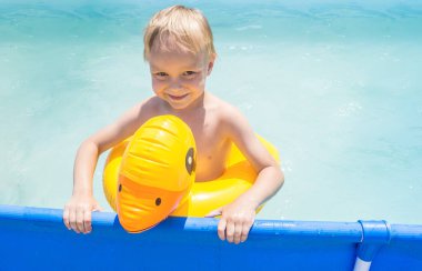 Hasır şapkalı lastik ördekli çocuk. Ahşap arka. Taze trend rengi. Havuz gezisi