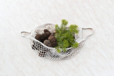 Sıfır Noel konsepti. Doğal Noel süslemeleri, çam kozalakları ve keten çantada dallar. Düz yatış, üst görünüm