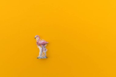 Flamingo plastik bir torbaya dolanmış. Plastik hayvan konsepti. Sarı arka plan. Çevre kirliliği sorunu.