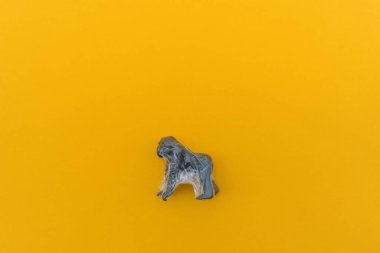 Goril plastik bir torbaya dolanmış. Plastik hayvan konsepti. Sarı arka plan. Çevre kirliliği sorunu.