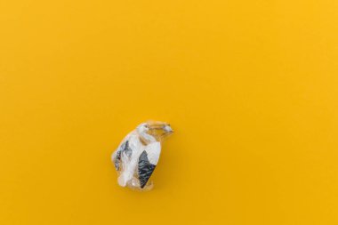 Pelikan plastik bir torbaya dolanmış. Plastik hayvan konsepti. Sarı arka plan. Çevre kirliliği sorunu.