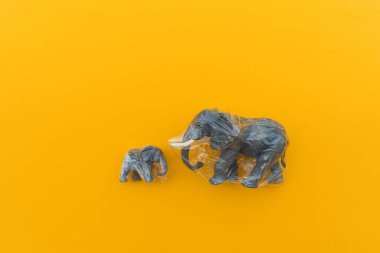 Fil plastik bir torbaya dolanmış. Plastik hayvan konsepti. Sarı arka plan. Çevre kirliliği sorunu.