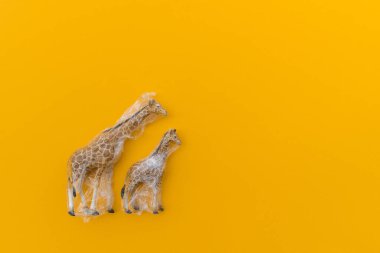 Zürafa plastik bir torbaya dolanmış. Plastik hayvan konsepti. Sarı arka plan. Çevre kirliliği sorunu.