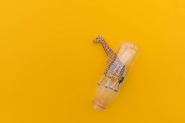 Zürafa plastik bir torbaya dolanmış. Plastik hayvan konsepti. Sarı arka plan. Çevre kirliliği sorunu.