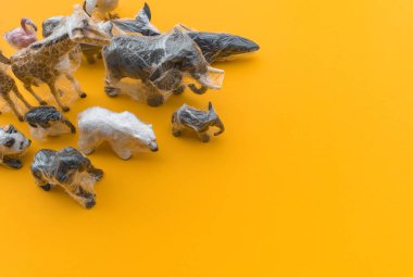 Hayvanlar plastik bir torbaya doluşmuş. Plastik hayvan konsepti. Sarı arka plan. Çevre kirliliği sorunu. Boşluğu kopyala