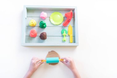 Montessori maddesi plastiktir. Şef eğitimi oyunu. Tahta tepside çocuk elleri. Beyaz arkaplan