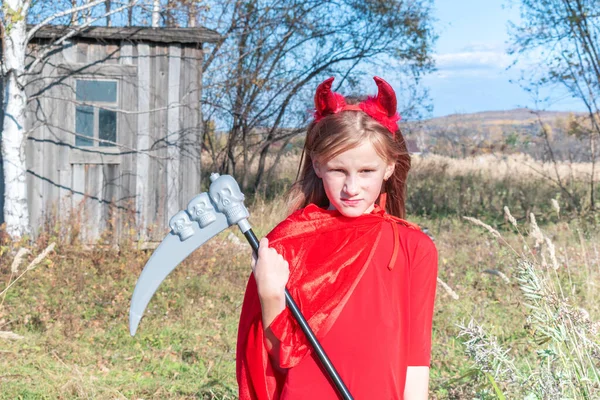 角のある悪魔の衣装の子供 赤いマントと怖い顔の感情 — ストック写真
