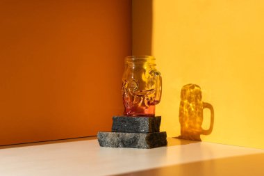 Komik Cadılar Bayramı dekorasyon partisi. Turuncu arka planda cam bir kafatası. Pencereden gelen güneş ışığı. Eğilim gölgesi