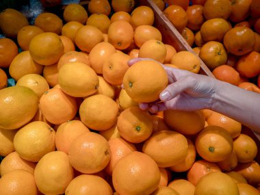 Bir el bir sunkist meyve ve sebze reyonunda turuncu süpermarkette alır.