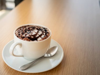 windows yakınındaki ahşap masa üzerinde beyaz bir fincan sıcak çikolata