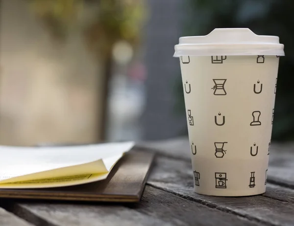Paper cup of coffee and bar menu on wooden table. Place for text.