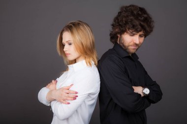 Genç Sarışın kadın ve esmer adam arka arkaya stand. Kavga, yanlış anlama. Studio gri bir arka plan üzerinde çekilen fotoğraf