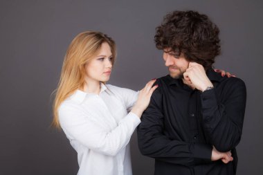 Genç Sarışın kadın esmer bir adam rahatlatıyor. Gri bir arka plan üzerinde atış stüdyo