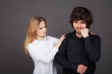 Genç Sarışın kadın esmer bir adam rahatlatıyor. Gri bir arka plan üzerinde atış stüdyo