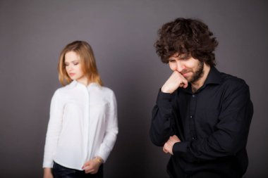 üzgün esmer adam sarışın genç bir kadın, arkasındaki sorunları yaşıyor, bir erkekle sempati. Studio gri bir arka plan üzerinde çekilen fotoğraf