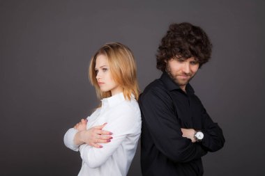 Genç Sarışın kadın ve esmer adam arka arkaya stand. Kavga, yanlış anlama. Studio gri bir arka plan üzerinde çekilen fotoğraf