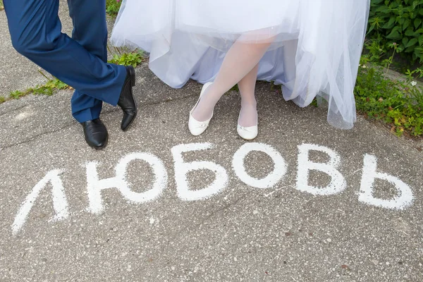 Inscription amour en russe sur la route. jambes du marié et du marié — Photo